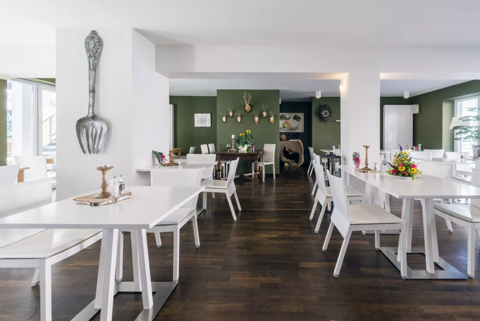 Apparthotel Bad Schandau – Hotel in Bad Schandau 3 Frühstücksbereich des Apparthotels mit Tischen und Stühlen in weiß, Parkettboden und grün gestrichener Wand