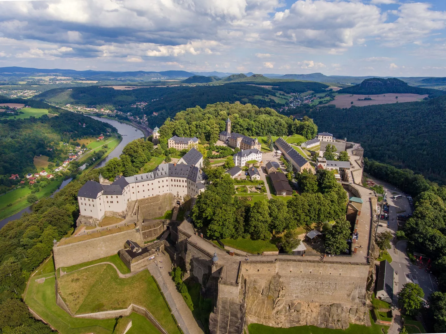 Festung Königstein aus der Vogelperspektive, von oben geschossen mit der gesamten Festung, dem Fluss der Elbe und Hügel in der Region, im Sommer mit blauem Himmel und ein paar Wolken