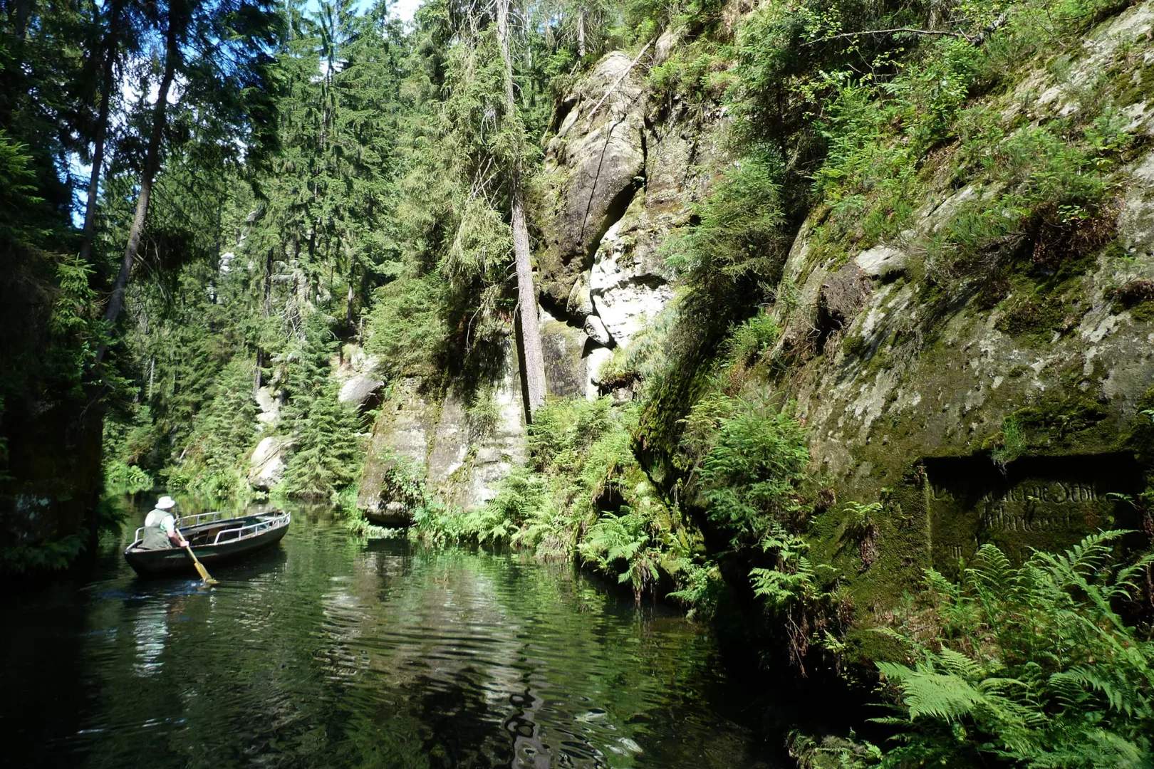 Kirnitschklamm in der Sächsischen Schweiz mit Felsen rum und Boot auf Wasser mit Mann im Boot der rudert