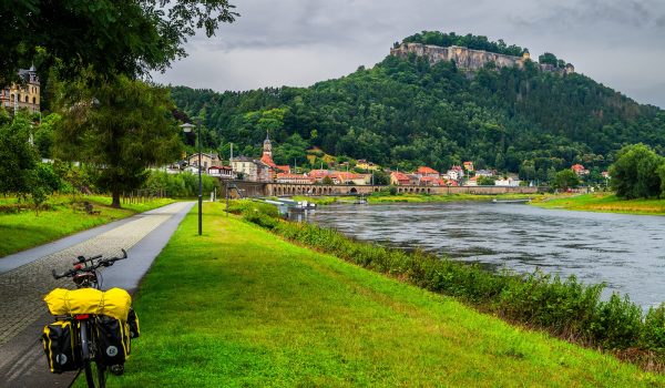 Foto vom Elberradweg, direkt entlang der Elbe mit der Festung Königstein und dem Dorf Königstein im Hintergrund