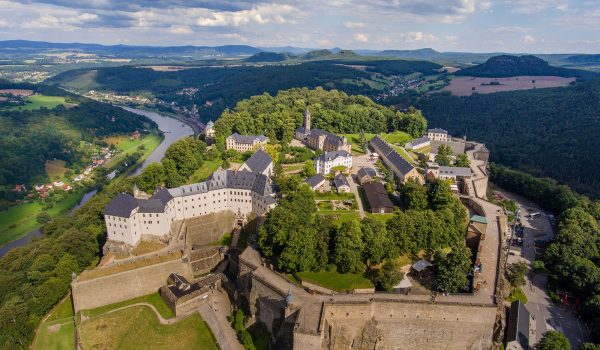 Festung Königstein aus der Vogelperspektive, von oben geschossen mit der gesamten Festung, dem Fluss der Elbe und Hügel in der Region, im Sommer mit blauem Himmel und ein paar Wolken