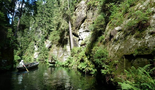 Kirnitschklamm in der Sächsischen Schweiz mit Felsen rum und Boot auf Wasser mit Mann im Boot der rudert